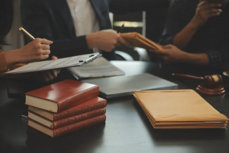 Justice and Law concept. Legal counsel presents to the client a signed contract with gavel and legal law or legal having team meeting at law firm in background